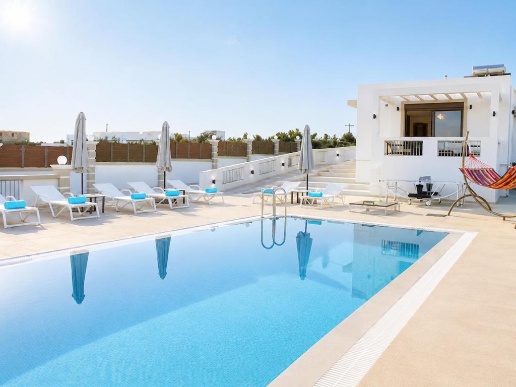 a pool with chairs and a hammock on a roof at Luxury Villa John in Panormos Rethymno