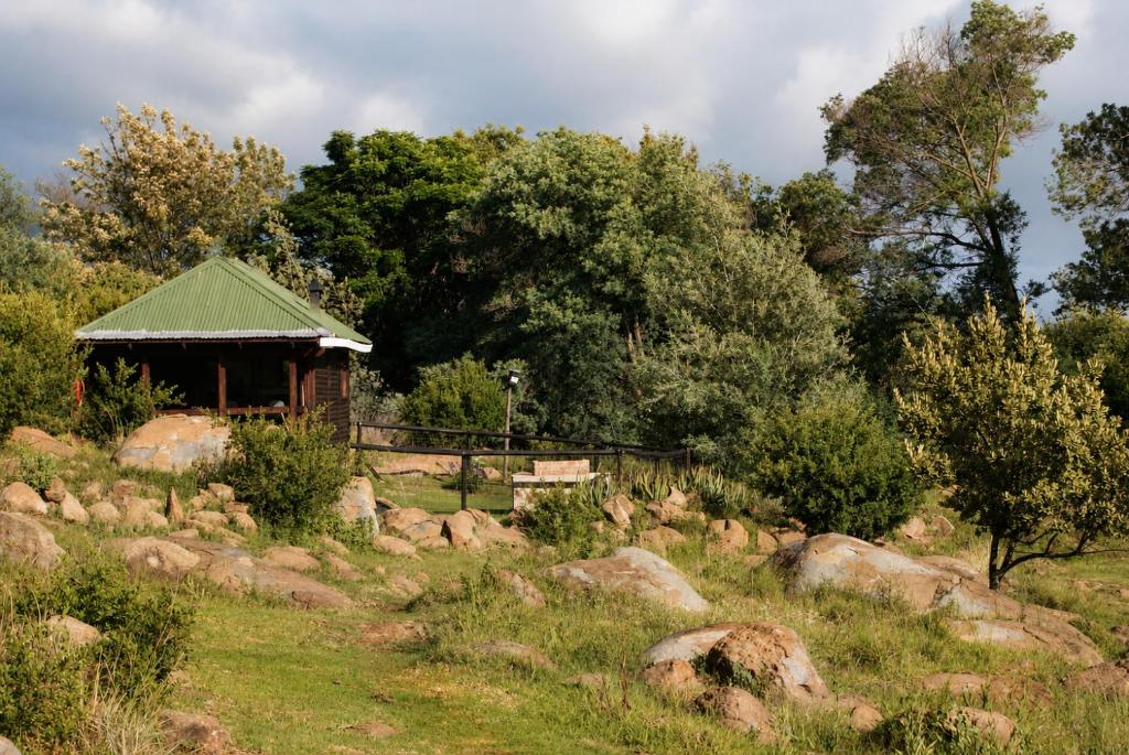 a building in a field with rocks and trees at Riverman Cabin Country Lodge - Tonteldoos in Tonteldoos