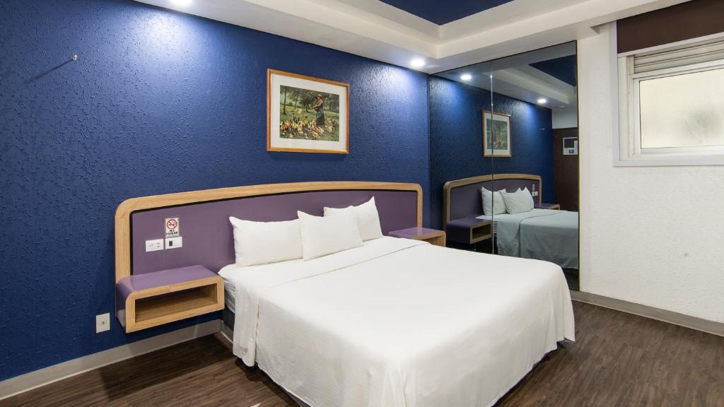 ein Schlafzimmer mit einem großen Bett und einer blauen Wand in der Unterkunft Hotel Menara in Mexiko-Stadt