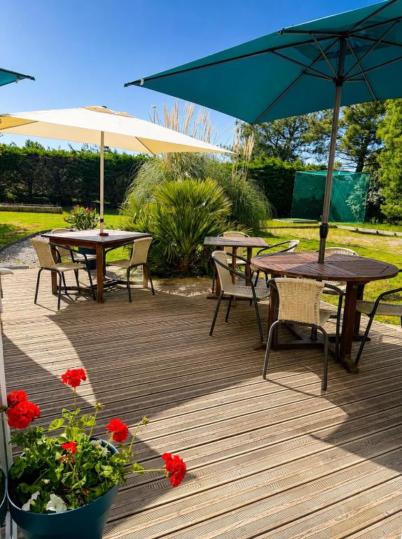 two tables and chairs with umbrellas on a wooden deck at Eurocéan Adonis Budget in Guérande
