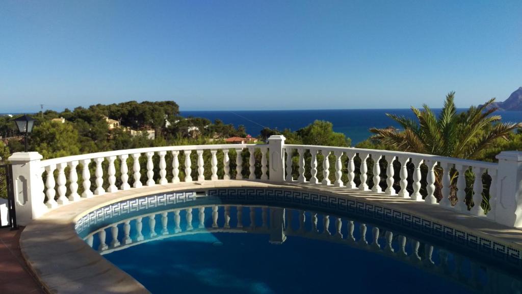 a swimming pool with a white fence and the ocean at Traumhaftes Apartment mit Pool in Altea