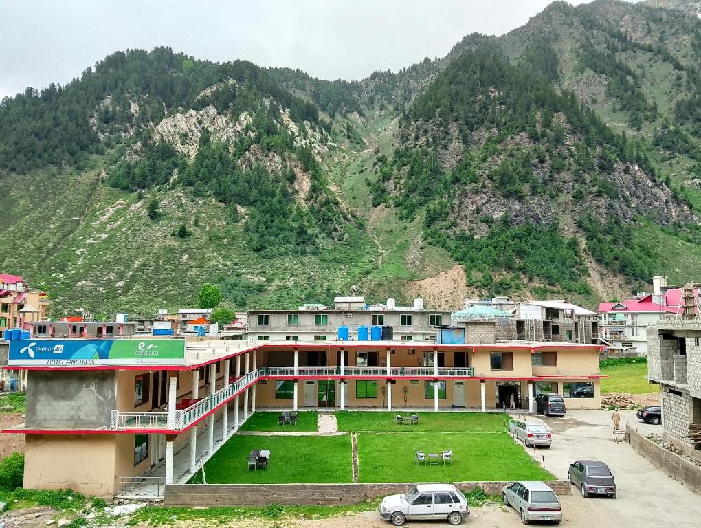 a building with a green lawn in front of a mountain at Pine Hills, Naran in Naran