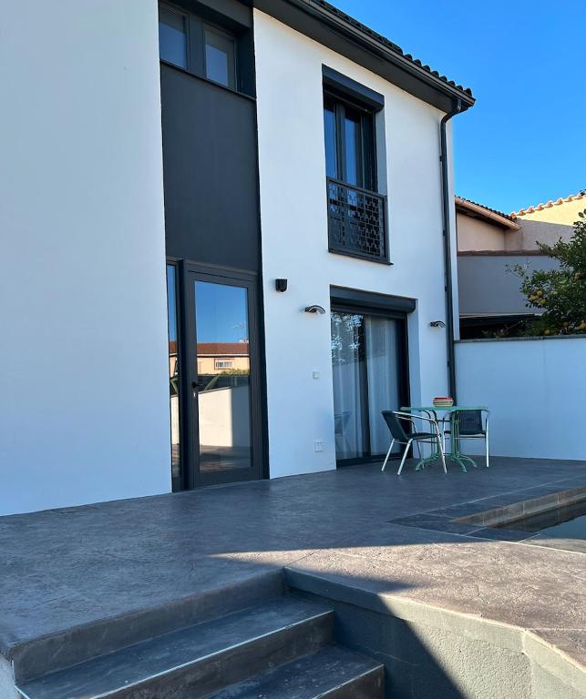 a white house with a patio with a table and chairs at La Perpignanaise in Perpignan