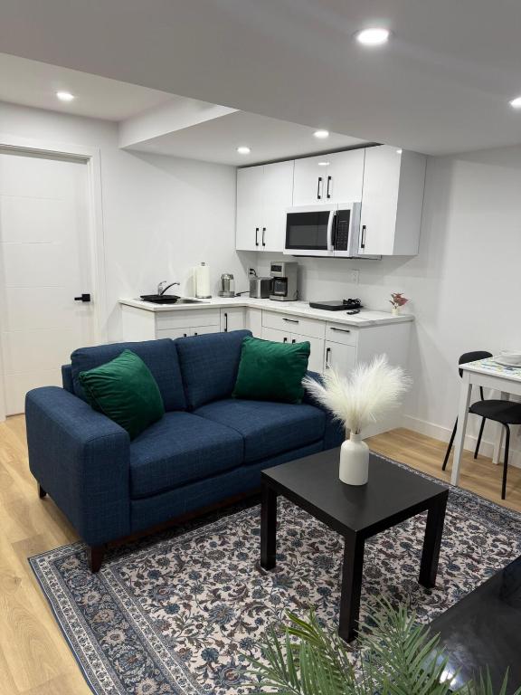 a living room with a blue couch and a kitchen at Cosy and Cute Private Basement Suite in Winnipeg