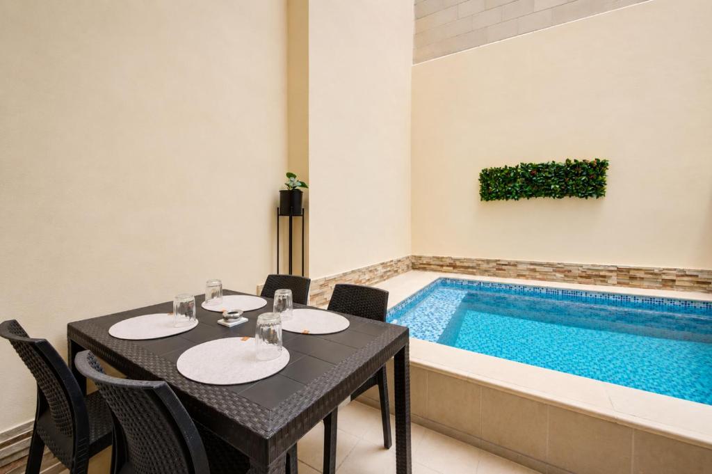 a dining table with chairs next to a swimming pool at Modern Duplex Apartment with Private Pool & AC Central Malta in Balzan