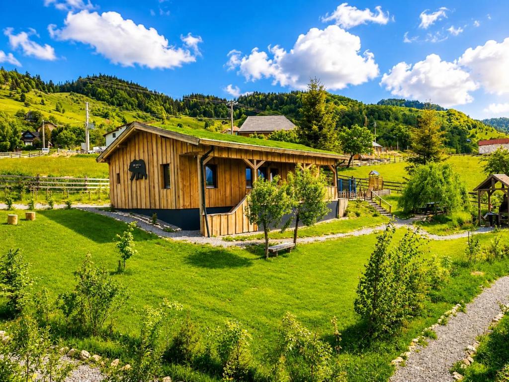 a wooden cabin in a green field with a hill at Casa WEZLY 2 in Măgura