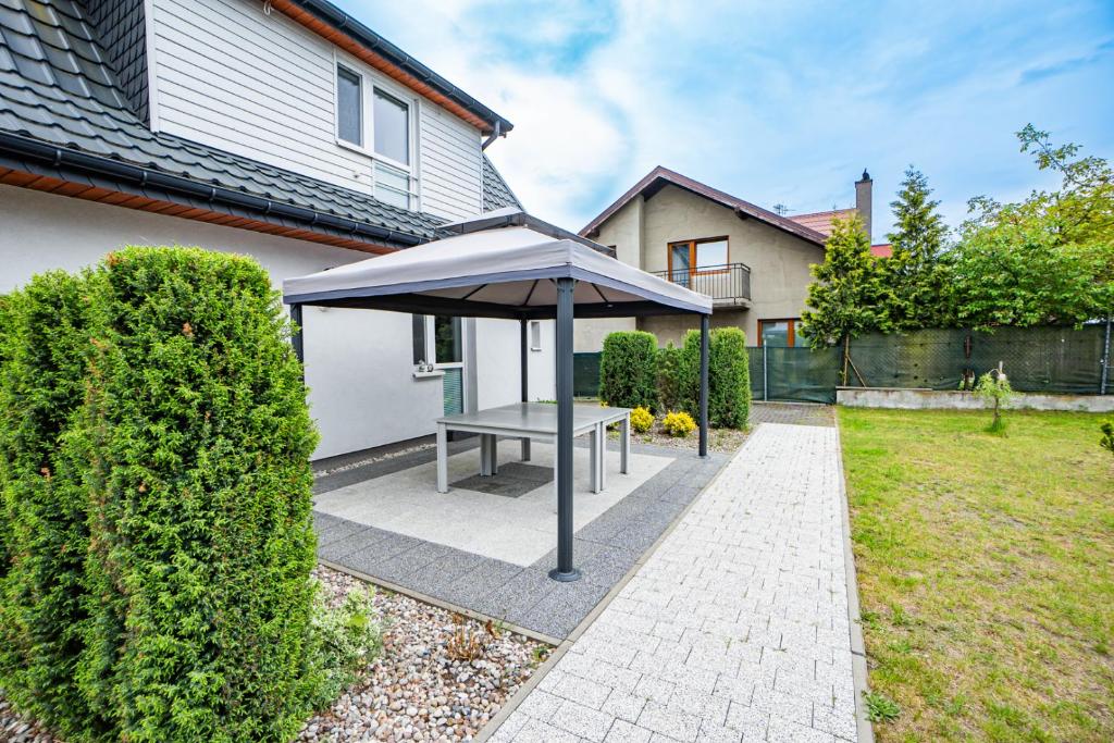 a picnic table under an umbrella in a backyard at Dwie Sowy by Baltic Home in Międzyzdroje