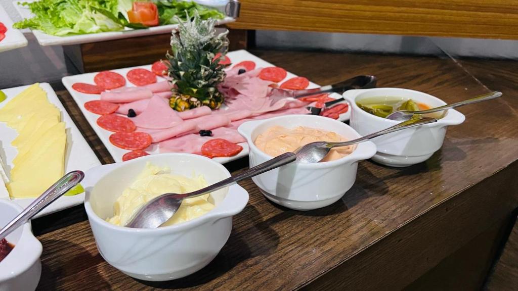 A compact buffet counter with sliced cheeses, cold cuts and condiments.