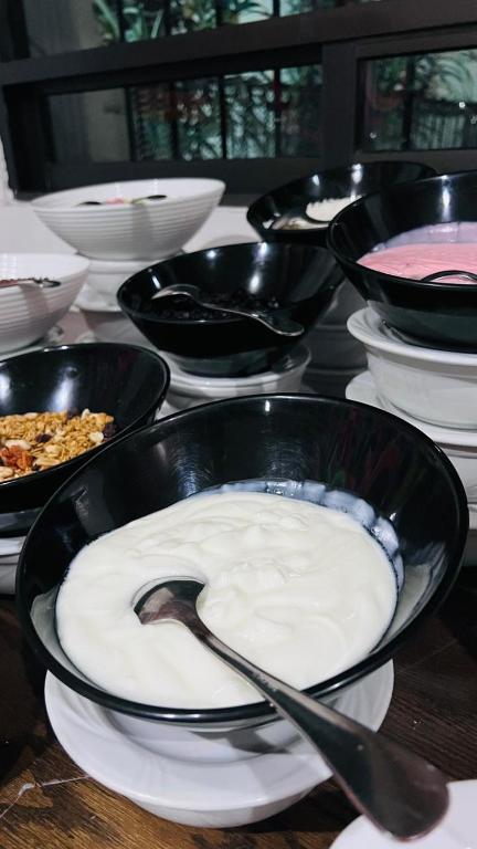 Breakfast bowls of yogurt, fruit and cereal arranged beside a window.