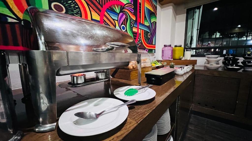 A buffet counter with covered hot food, plates and serving utensils.