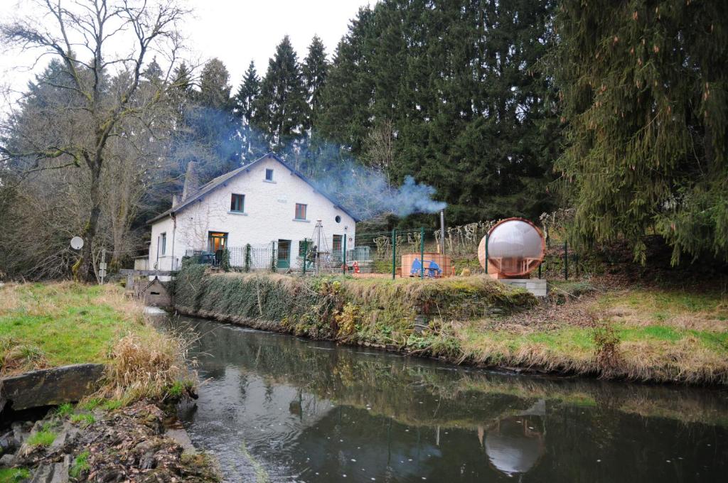 a white house next to a river with a barn at Moulin de Nawes in Herbeumont