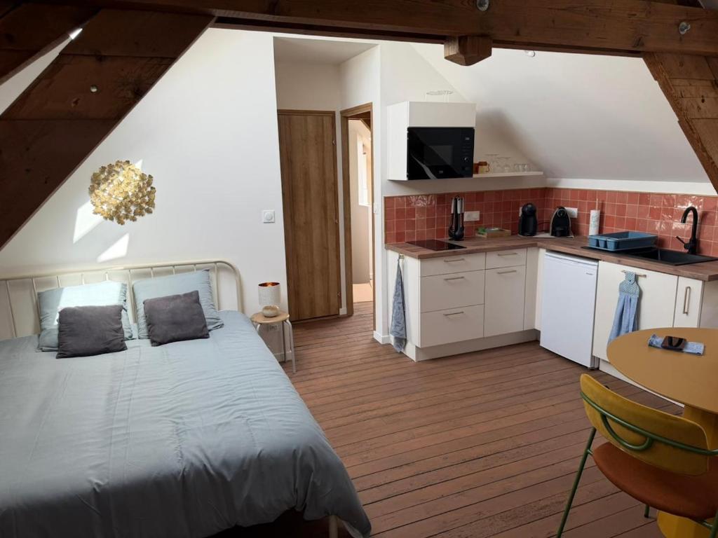 a bedroom with a large bed and a kitchen at Le Studio in Milly-sur-Thérain