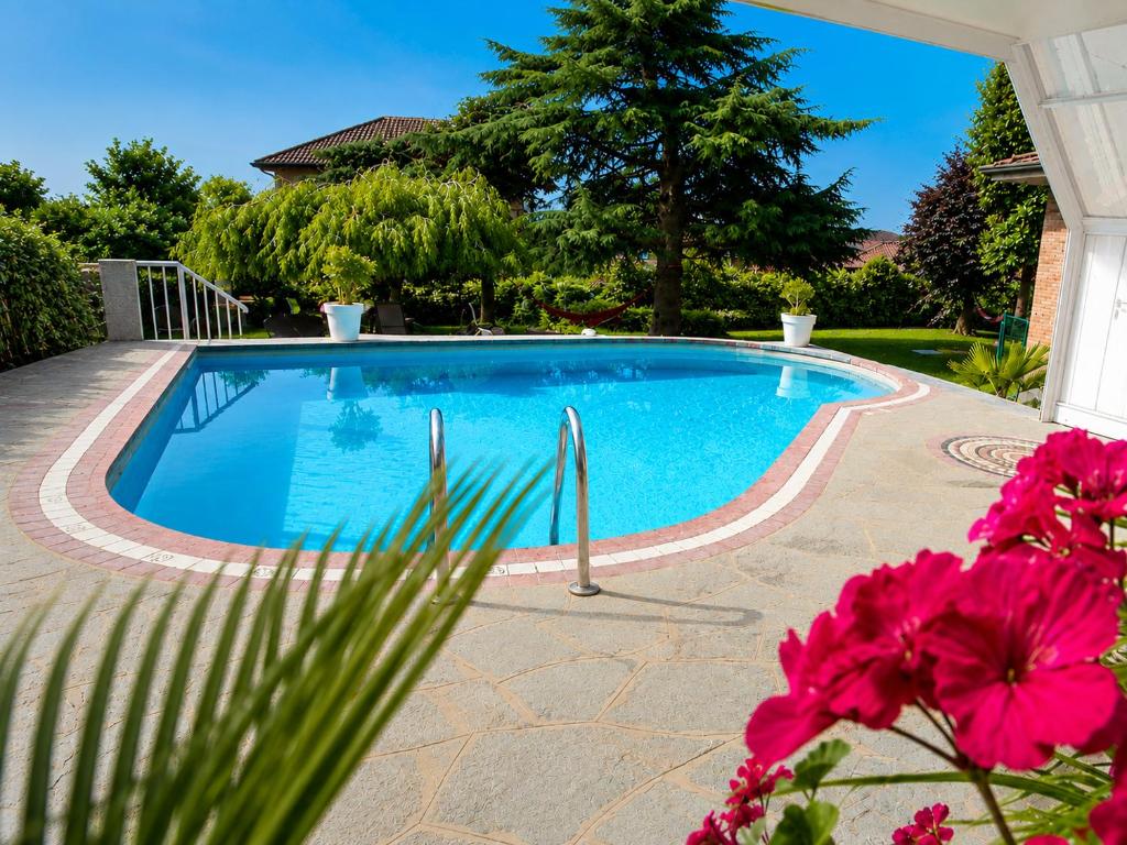 a swimming pool in a yard with pink flowers at VillaCuore in Tavernerio