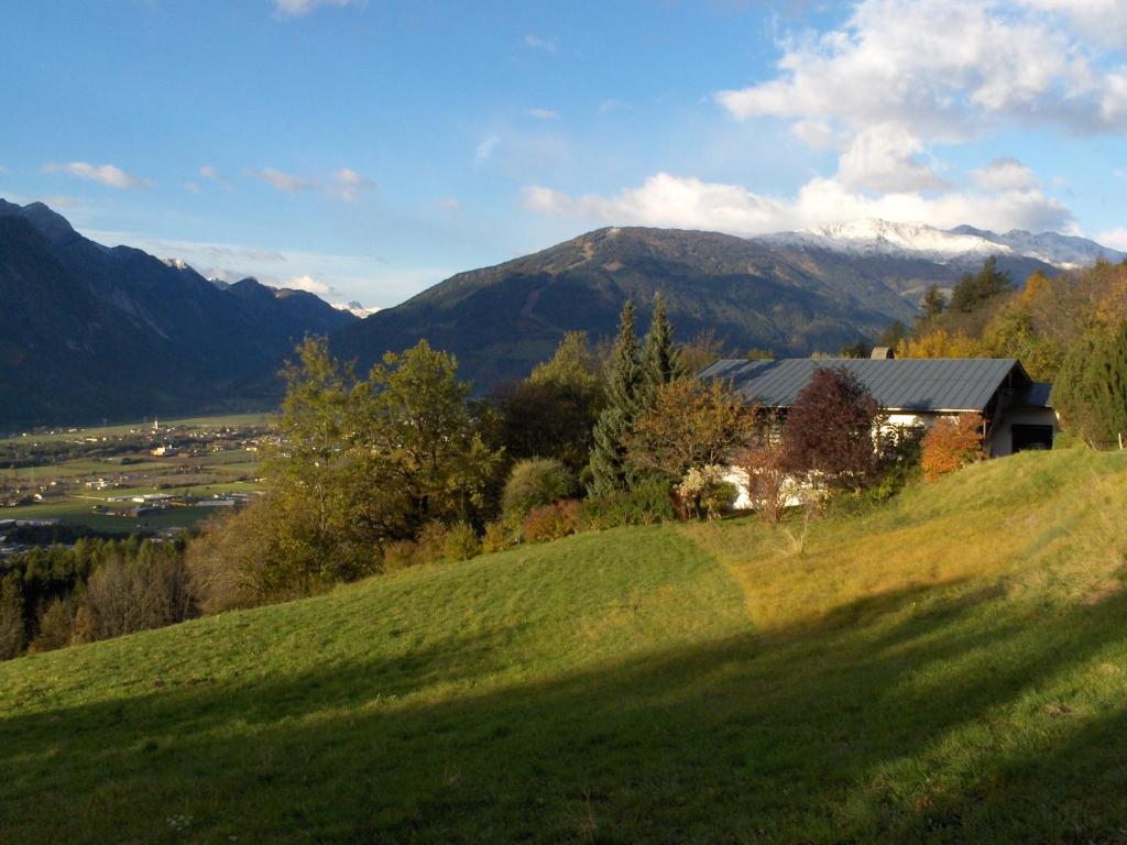 ein Haus auf einem Hügel mit Bergen im Hintergrund in der Unterkunft Ferienwohnung Barbara Mair in Dölsach