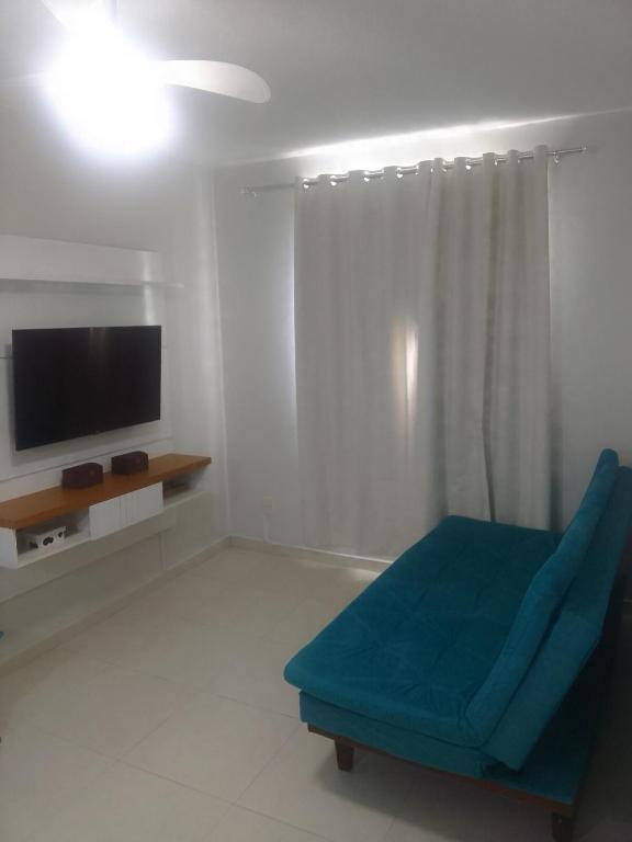 a living room with a blue couch and a television at Praia da Costa próx da Praia in Vila Velha