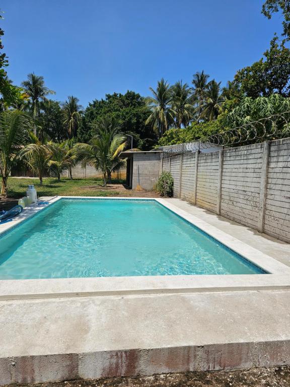 a swimming pool in a backyard with a fence and trees at Honey Beach House in La Esmeralda