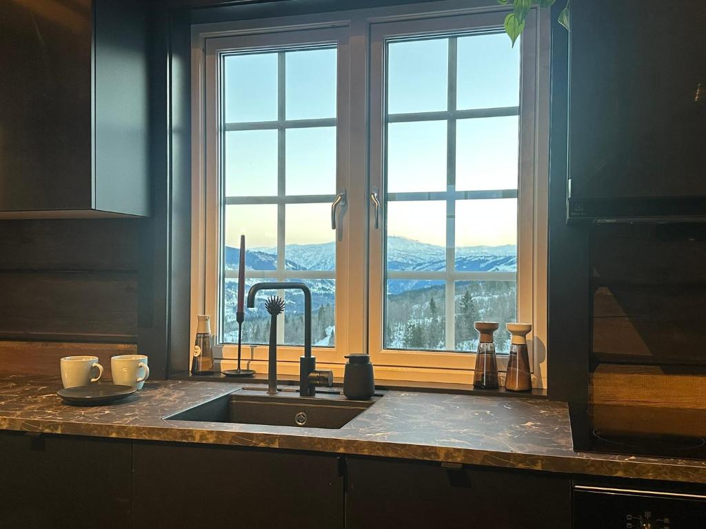 a kitchen counter with a sink and a window at Log cabin in Hodlekve with mountain view in Sogndal