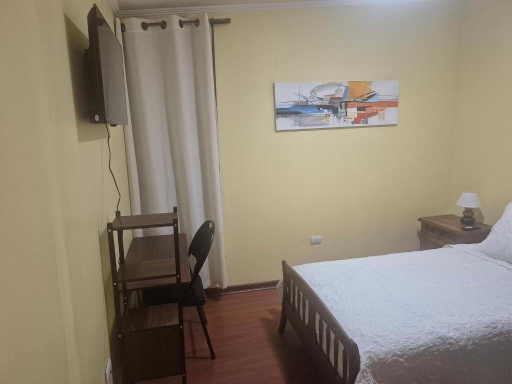 a bedroom with a bed and a television and a chair at casa completa e independiente en 2 piso in Antofagasta