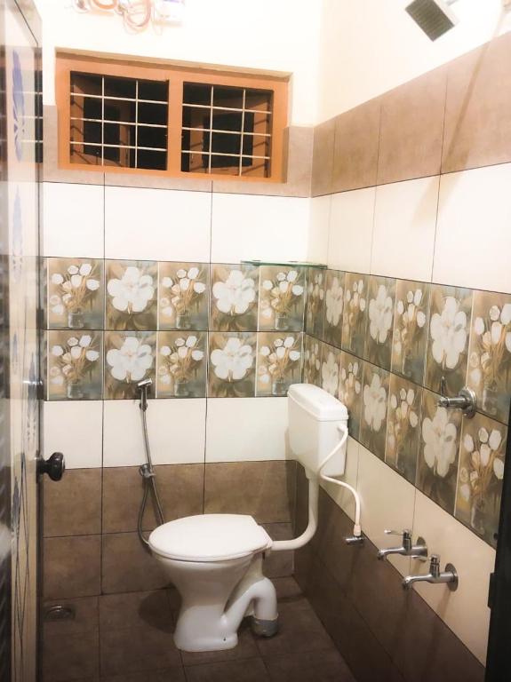 a bathroom with a toilet and flowers on the wall at Palm paradise in Kadavoor