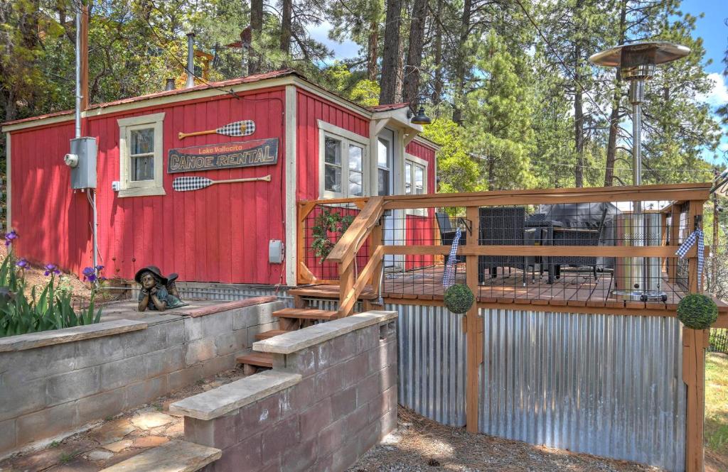 a dog sitting in front of a red tiny house at Red Bungalow Vallecito Studio Cabin near Durango, CO in Bayfield