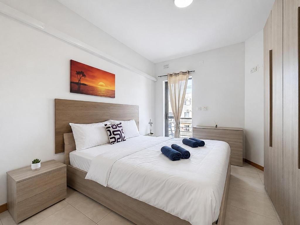 a bedroom with a bed with two blue pillows on it at Central Msida Modern Holiday Apartment in Tal-Ħriereb