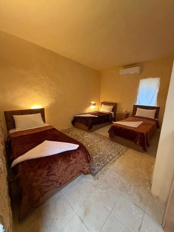a bedroom with three beds in a room at Mawasem Dana in Dana