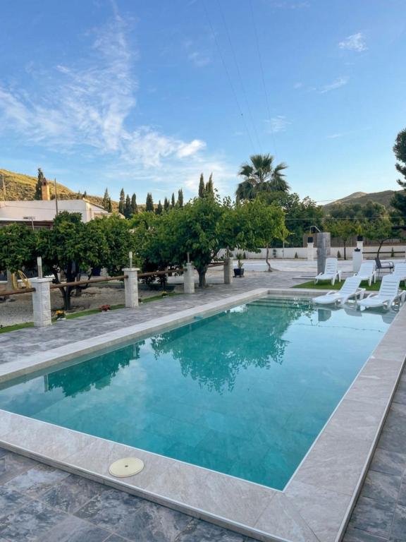 a swimming pool in a resort with chairs and trees at Villa Karma in Berja