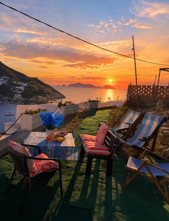 a table and chairs with a sunset in the background at Ponzamania Appartamenti da Silverio in Ponza