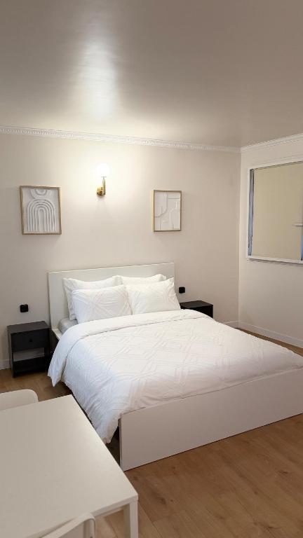 a white bedroom with a white bed and two tables at Studio Moderne - Proche 15mn Orly et 25mn Paris in Juvisy-sur-Orge