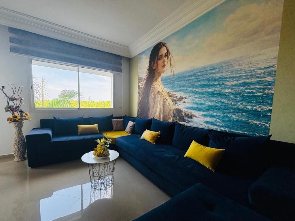 a living room with a blue couch and a painting of a woman at perfect 2 bedrooms 2 balconies pool and golf in Asilah