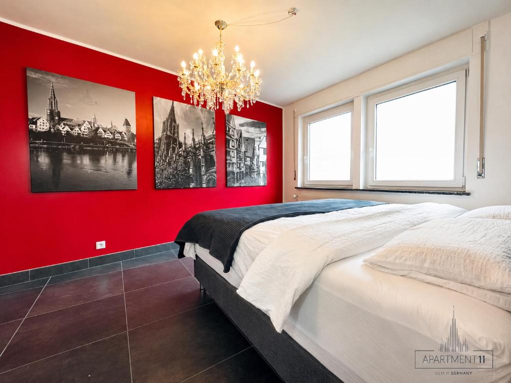 a red bedroom with a large bed and a chandelier at apartment11 in Ulm