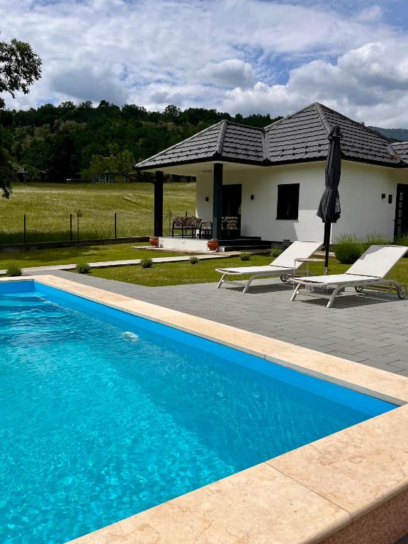 a swimming pool in front of a house at Mali Raj in Banja