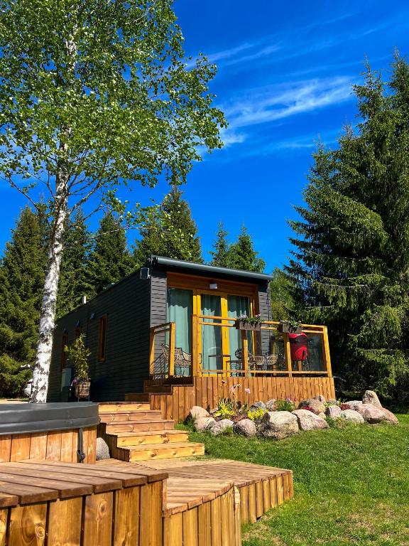a black tiny house with a deck and stairs at ARKA Puhkemajad in Päidre