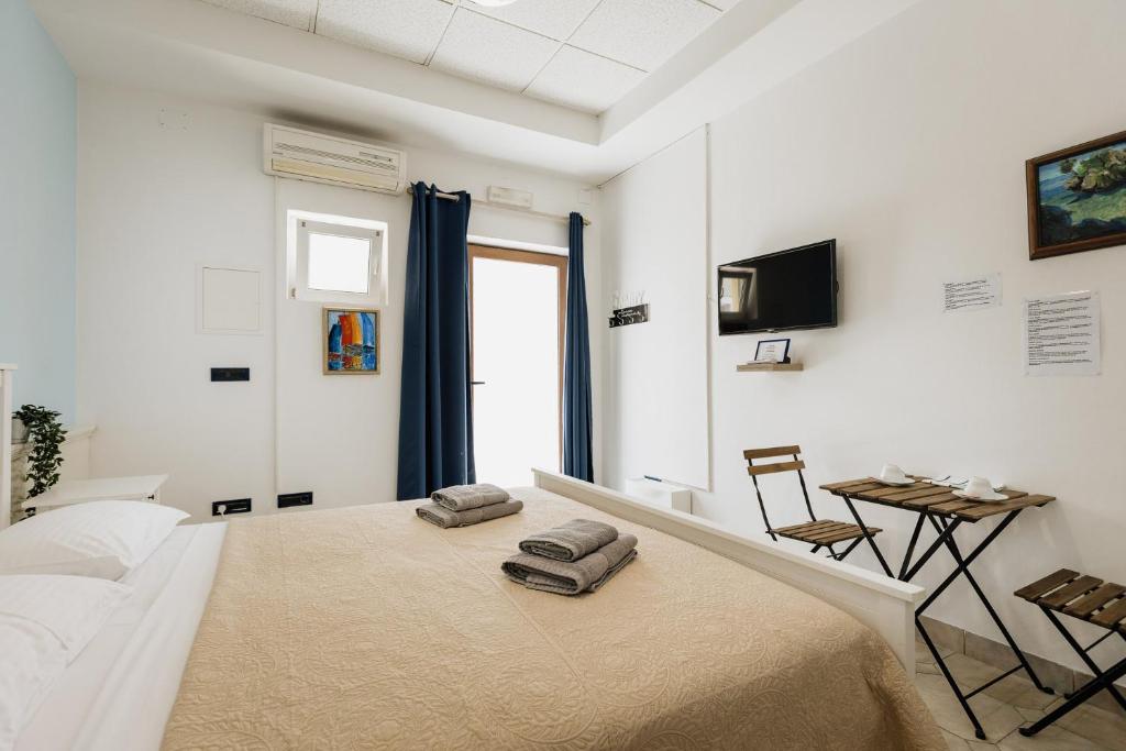 ein weißes Zimmer mit einem Bett, einem Tisch und einem Fernseher in der Unterkunft RIO - nice room, near the sea and park in Novigrad Istria