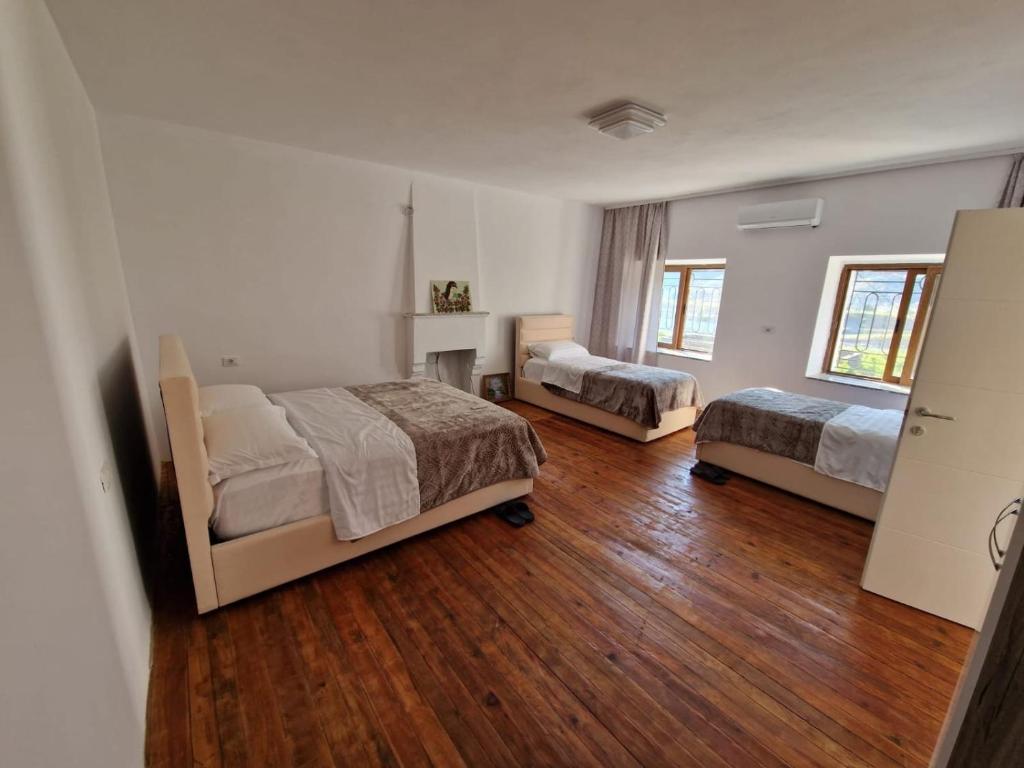 a bedroom with two beds and a wooden floor at Bujtina Dalmacia in Shkodër
