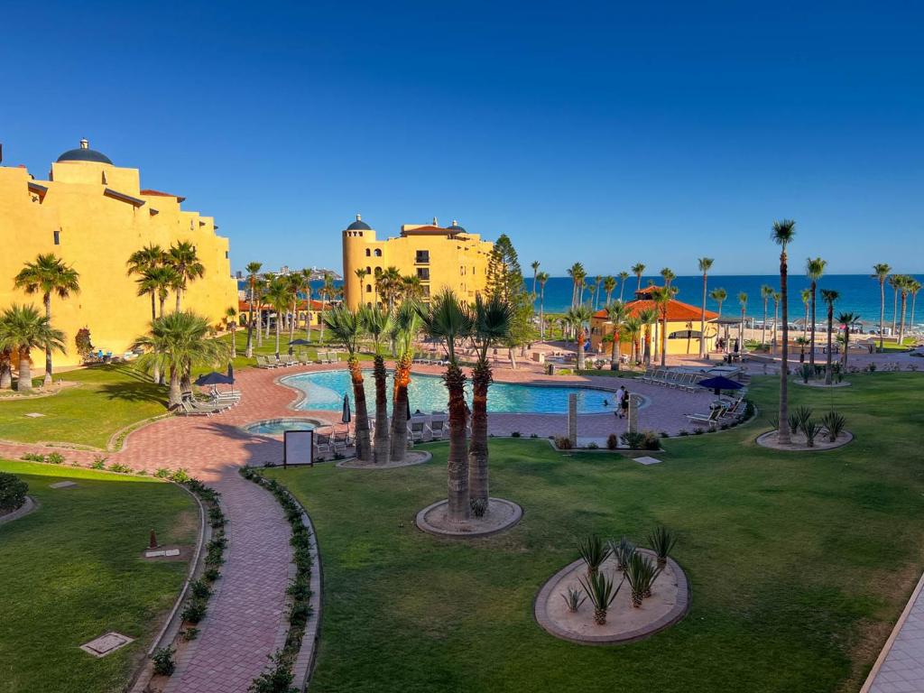 a resort with a swimming pool and palm trees at Sandy Beach Princesa B309 Ocean Front Resort in Puerto Peñasco