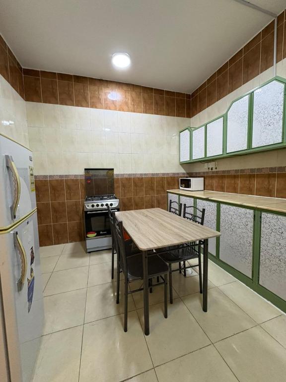 a kitchen with a table and chairs and a refrigerator at Asus Al Taj Serviced Apartments in Baish