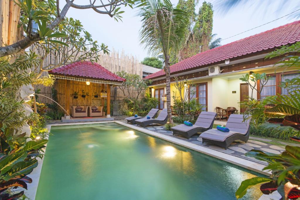 a pool in the backyard of a home with chairs and a house at Sandat Bali Ubud in Ubud