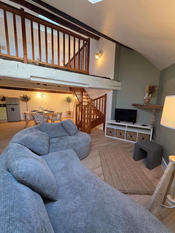 a living room with a blue couch and a staircase at L'Écrin Historique - Duplex - Vieux Chaumont in Chaumont