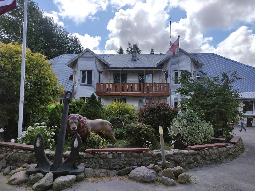 a house with a statue of a dog in front of it at Atpūtas vieta- Mini ZOO BUKI in Vārve