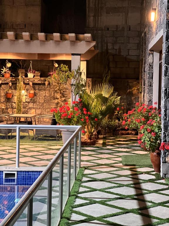 a patio with flowers and a swimming pool at شالية الشفق in Al ‘Aqar