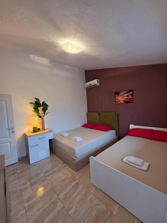 a bedroom with two beds and a night stand and a table at Apartmani Tina in Sutomore