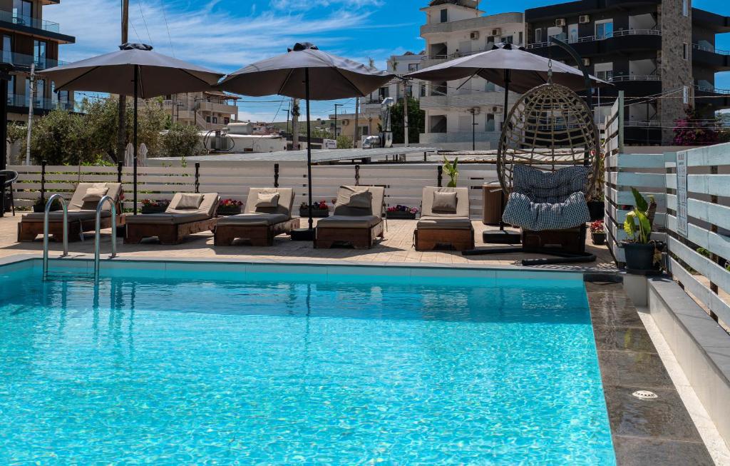 a swimming pool with chairs and umbrellas next to a building at Noa Boutique Hotel in Ksamil
