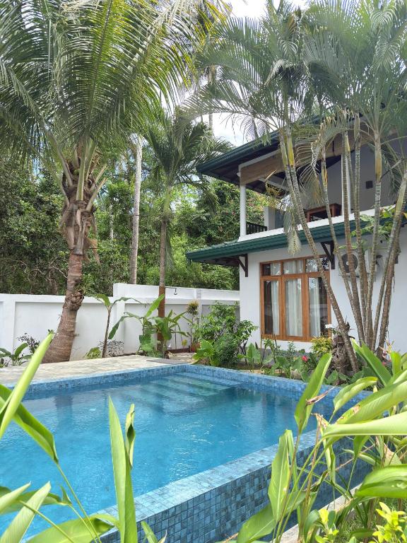 a swimming pool in front of a house with palm trees at All View Resort in Tangalle