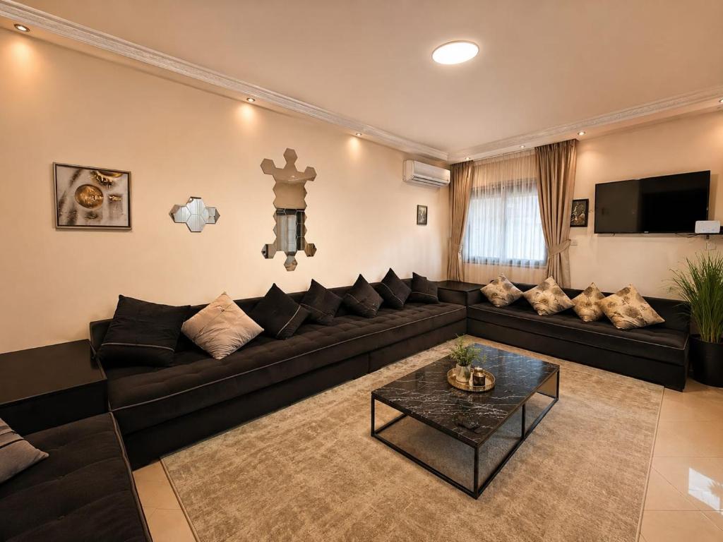 a living room with a black couch and a table at Meknes Hamria centre ville only families and forneigners in Meknès