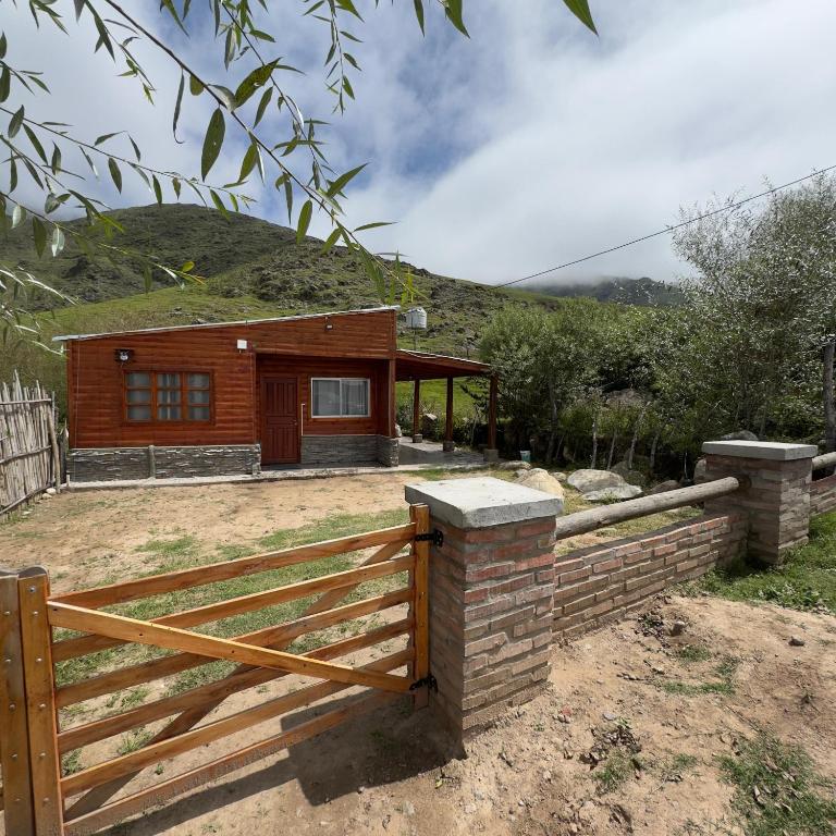 a wooden house with a fence in front of it at Cabaña Arashi in Tafí del Valle