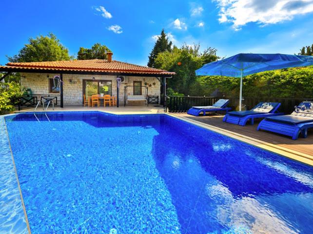 a blue swimming pool with two blue chairs and an umbrella at Villa Defne Kaş in Cukurbag