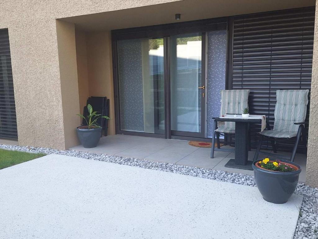 a patio with two chairs and a table on a house at Sunlit Oasis Garden in Postojna