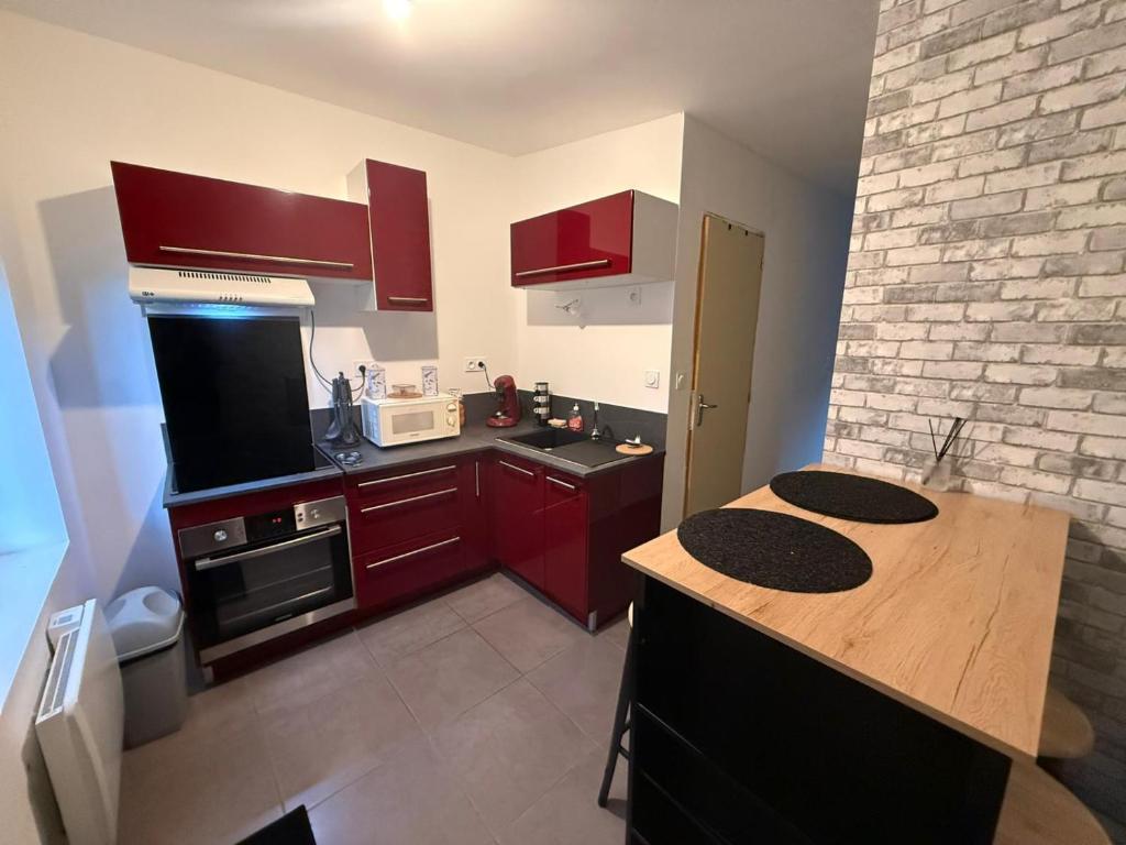 a small kitchen with red cabinets and a counter top at Petit studio charmant in Lezoux