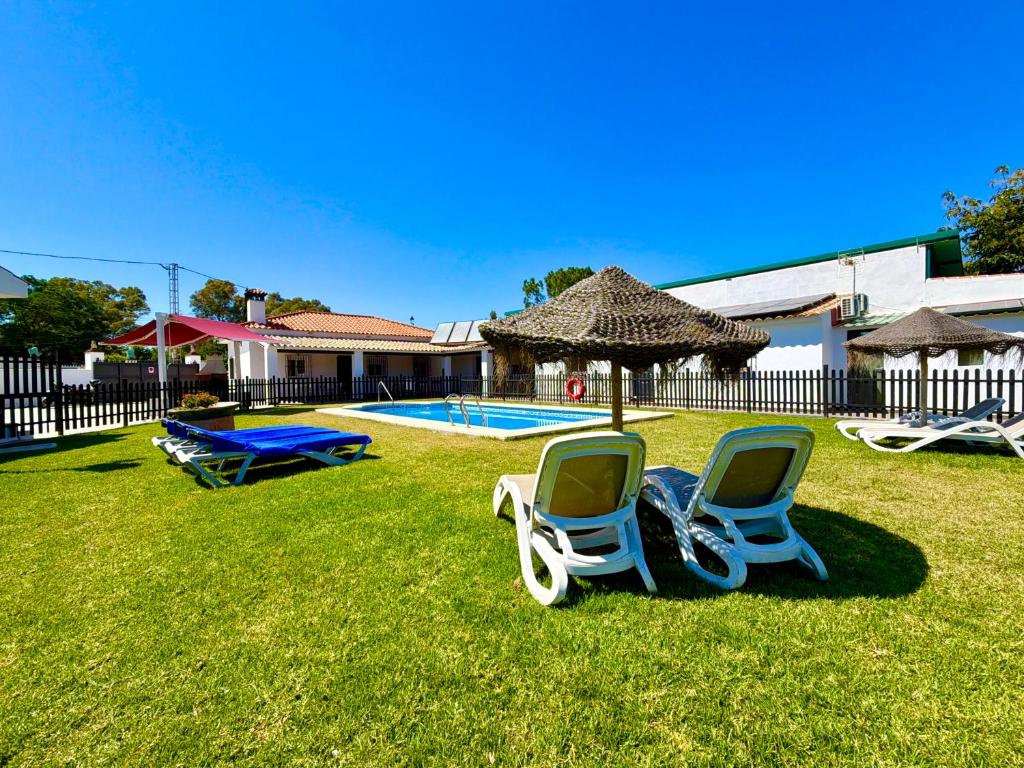 two chairs sitting in the grass near a swimming pool at El Naranjo del Abuelo in Málaga